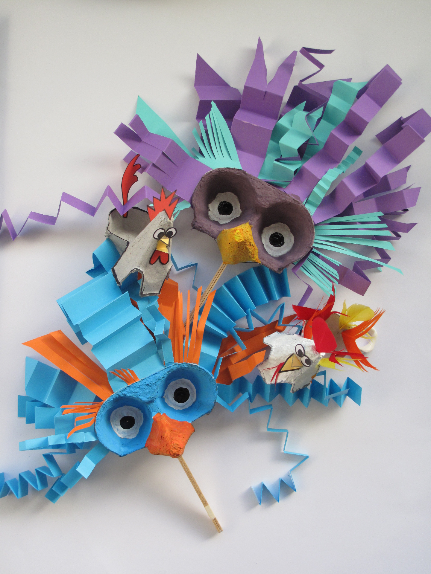 Vibrant handmade paper and egg-carton bird masks with purple, teal and orange feathers